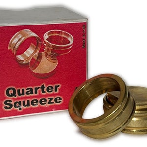 May include: A set of two gold-colored metal rings, one larger than the other, with a smaller, flat, gold-colored metal disc. The rings are labeled "Quarter Squeeze" on a red box with white trim. "Made in India" is printed on the side of the box.