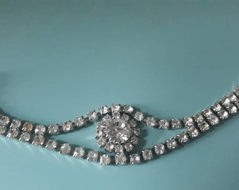 May include: A silver rhinestone bracelet with a large, round rhinestone in the center.