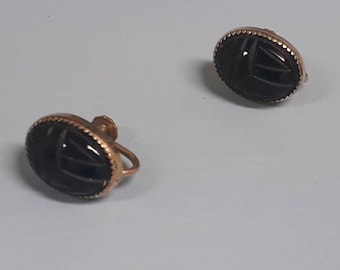 May include: A pair of gold tone clip-on earrings with black scarab beetle designs.