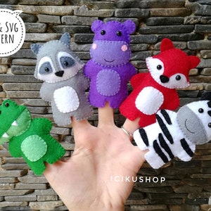 Può includere: Cinque pupazzi per dita in feltro, tra cui un ippopotamo viola, un procione grigio, una volpe rossa, un alligatore verde e una zebra in bianco e nero. Tutti i pupazzi sorridono e hanno facce amichevoli. Il testo "PDF & SVG PATTERN" è visibile nell'angolo in alto a sinistra dell'immagine.