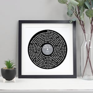May include: A black and white framed print of a vinyl record with the lyrics to the song "Make You Feel My Love" by Adele. The lyrics are printed in a circular pattern around the centre of the record.