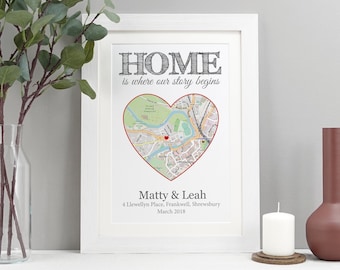 May include: A white framed print with the text "HOME is where our story begins" and a heart-shaped map of a city. The names "Matty & Leah" are printed below the map, along with an address and date.