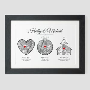 May include: A black framed print with a white background and black text. The text reads "Holly & Micheal". There are three maps with red hearts marking locations. The text below the maps reads "First Met, Small Wood Pines, 8th June 2016", "Engaged, Lodge Park, 21st March 2021", and "Married, Appleton Thorn Church, 21st March 2022".