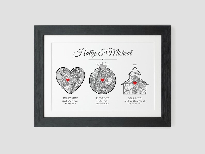 May include: A black framed print with a white background and black text. The text reads "Holly & Micheal". There are three maps with red hearts marking locations. The text below the maps reads "First Met, Small Wood Pines, 8th June 2016", "Engaged, Lodge Park, 21st March 2021", and "Married, Appleton Thorn Church, 21st March 2022".