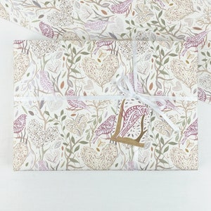 May include: White gift wrap with a repeating pattern of stylised birds, leaves, and hearts in shades of pink, brown, and green.