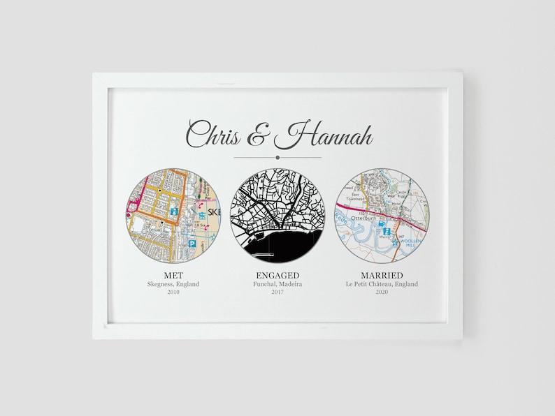 May include: A black and white map print with three circles showing the locations where a couple met, got engaged, and married. The text reads "Chris & Hannah" and includes the locations and years of each event.