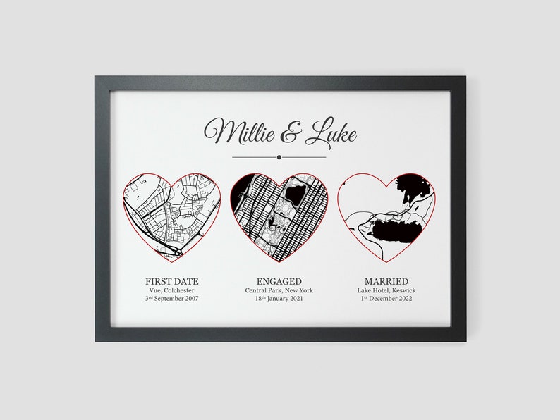 Pu&ograve; includere: Una stampa di mappa in bianco e nero con tre contorni di cuore rossi. I cuori mostrano le posizioni del primo appuntamento, del fidanzamento e del matrimonio di una coppia. Il testo recita "Millie & Luke", "Primo appuntamento, Vue, Colchester, 3 settembre 2007", "Fidanzati, Central Park, New York, 18 gennaio 2021", e "Sposati, Lake Hotel, Keswick, 1 dicembre 2022".