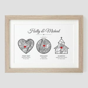 May include: A black and white map print with red hearts marking locations. The print is framed in a light wood frame and includes the text "Holly & Micheal", "First Met", "Engaged", and "Married" with corresponding dates.