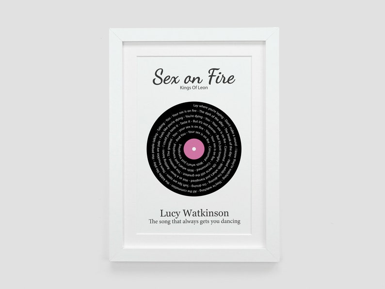 May include: A black and white framed print with a pink circle in the center. The print features a black vinyl record with the song lyrics for "Sex on Fire" by Kings of Leon. The text "Lucy Watkinson" and "The song that always gets you dancing" are printed below the record.
