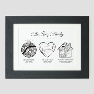 May include: A black and white print with the text "The Long Family" at the top. The print features three maps: a circle with a diamond ring, a heart, and a house. Each map is labeled with a location and date. The text below the maps reads "She said yes! Paris, France 15 March 2010", "We said I do! Caunton, England 18 April 2002", and "We got the keys! North Hykeham, England 23 November 2020".