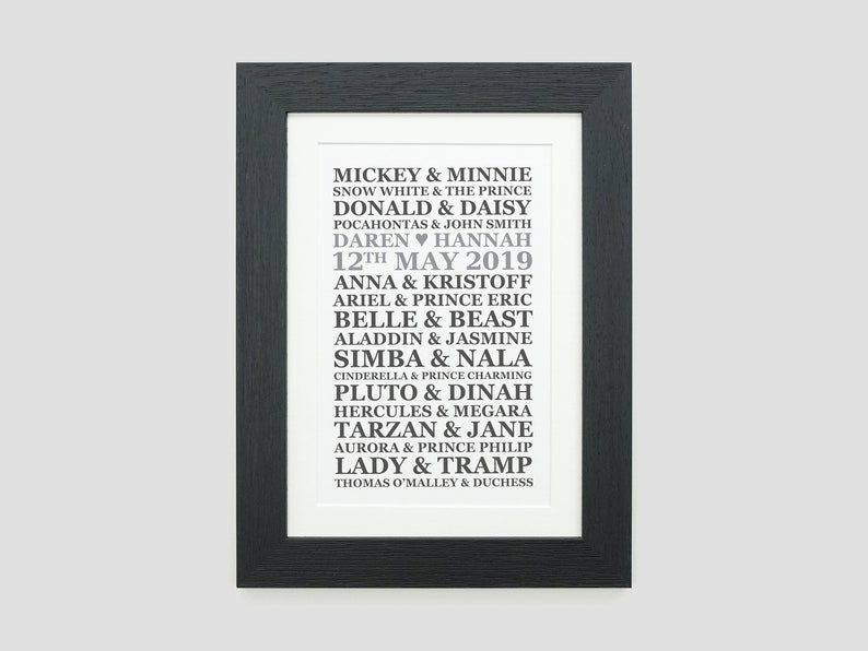May include: A black and white framed print with a list of Disney couples and their names. The text includes "Mickey & Minnie", "Snow White & The Prince", "Donald & Daisy", "Pocahontas & John Smith", "Daren Hannah", "12th May 2019", "Anna & Kristoff", "Ariel & Prince Eric", "Belle & Beast", "Aladdin & Jasmine", "Simba & Nala", "Cinderella & Prince Charming", "Pluto & Dinah", "Hercules & Megara", "Tarzan & Jane", "Aurora & Prince Philip", "Lady & Tramp", and "Thomas O'Malley & Duchess".