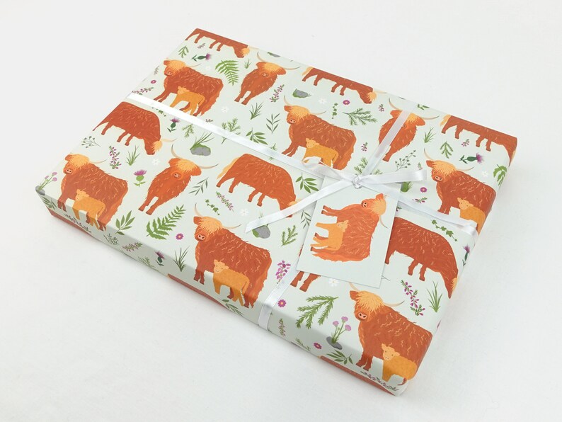 May include: Gift wrap featuring a repeating pattern of brown Highland cows with calves on a light green background with small flowers and leaves.