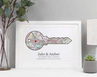 May include: A white framed print with a map of a neighborhood shaped like a key. The key has a red heart in the center. The text below the key reads "Jake & Amber 29 Swallow Road, Thetford Congratulations on your new home!"
