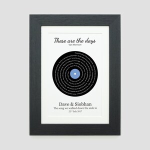May include: A black and white framed print with a black vinyl record design. The record has the lyrics to the song "These Are The Days" by Van Morrison printed on it. The text below the record reads "Dave & Siobhan, The song we walked down the aisle to, 22 July 2017."