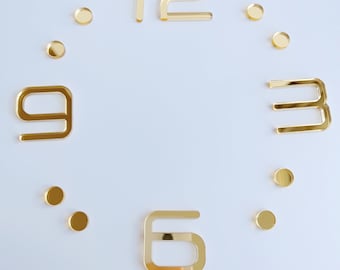 May include: Gold-colored clock face with Roman numeral 12, Arabic numerals 3, 6, and 9, and small gold circles for the remaining hours.