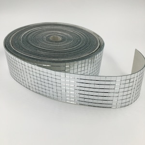 May include: A roll of silver self-adhesive mirror tile trim. The trim is made up of small square tiles that create a shimmering effect.