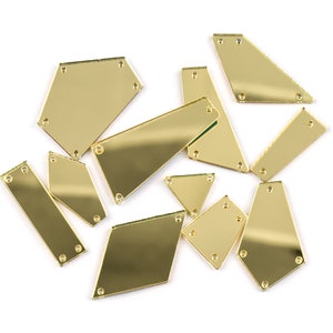 Peut inclure: Un ensemble de formes acryliques dorées en forme de miroir avec des trous dans les coins. Les formes sont de différentes tailles et comprennent des rectangles, des triangles et des diamants.