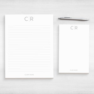 May include: Two white notepad sets with lined paper and the initials "CR" printed in gray at the top. The smaller notepad has the name "CLARK ROWE" printed at the bottom.