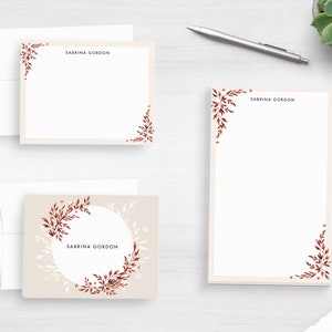 May include: Stationery set featuring a cream-colored notepad, notecards, and envelopes. The stationery is adorned with a delicate floral design in shades of red and brown. The name "SABRINA GORDON" is printed on the notepad and notecards.