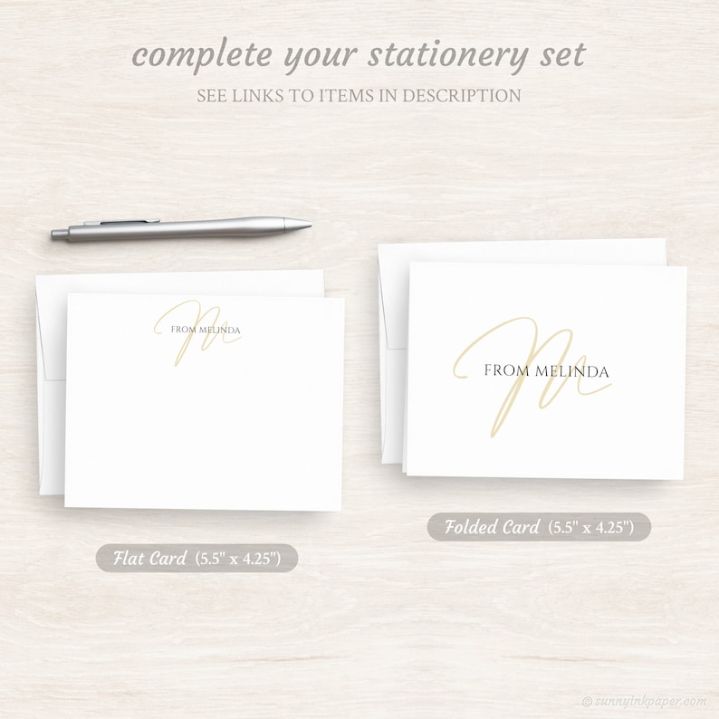 May include: Two white stationery cards with a gold script font that says "From Melinda". The card on the left is a flat card, and the card on the right is a folded card. Both cards are 5.5 inches by 4.25 inches.