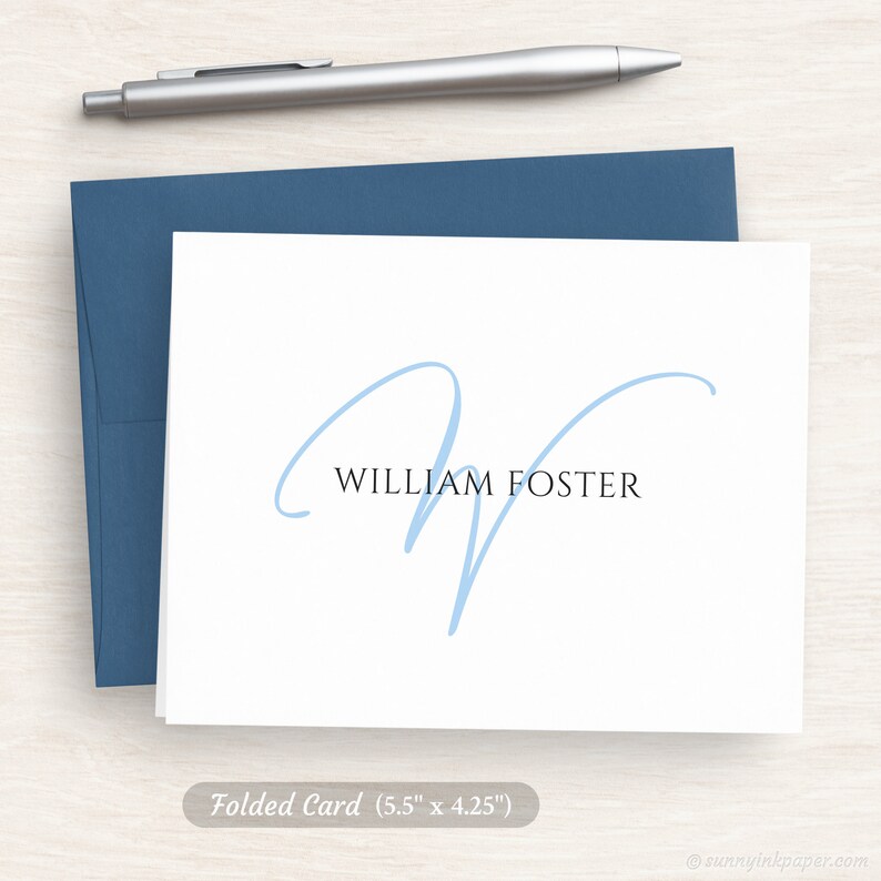 May include: A folded white card with a light blue cursive letter W and the text "WILLIAM FOSTER" printed in black.
