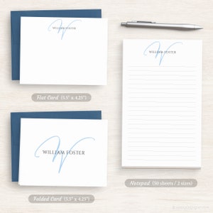 Op de afbeelding: Een set gepersonaliseerd briefpapier met een handgeschreven, lichtblauwe initiaal "W" met de naam "William Foster" eronder gedrukt. De set bevat een platte kaart, een gevouwen kaart en een notitieblok met 50 vellen.