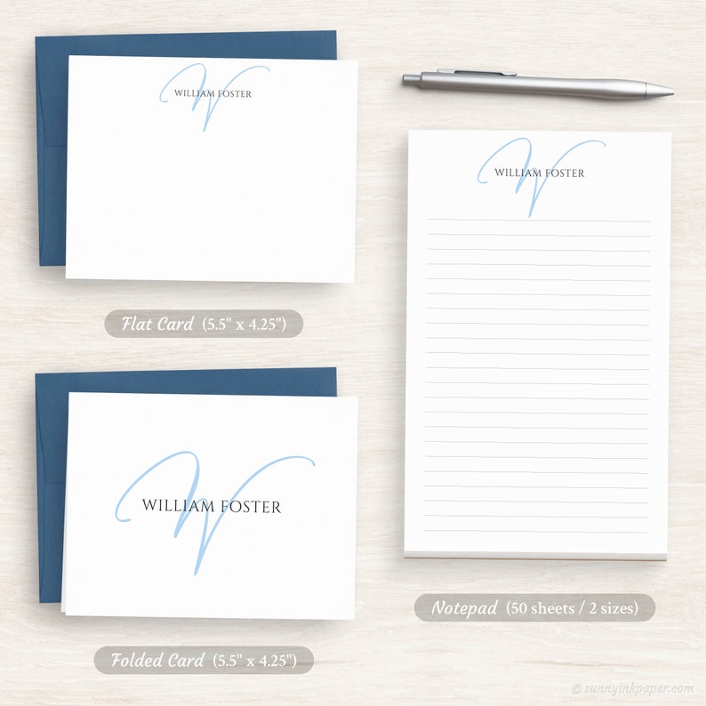 Op de afbeelding: Een set gepersonaliseerd briefpapier met een handgeschreven, lichtblauwe initiaal "W" met de naam "William Foster" eronder gedrukt. De set bevat een platte kaart, een gevouwen kaart en een notitieblok met 50 vellen.