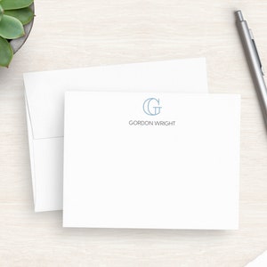 May include: A white stationery card with a blue and white monogram of the letter "G" and the text "GORDON WRIGHT" printed in blue.