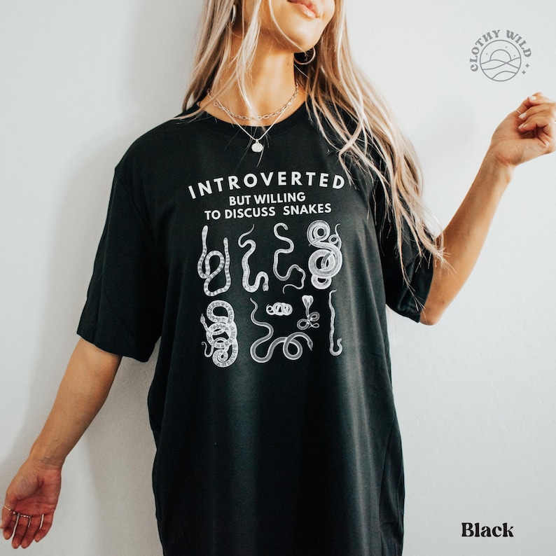 Puede incluir: Camiseta negra con el texto "Introvertido pero dispuesto a hablar de serpientes" y un gr&aacute;fico de varias serpientes.