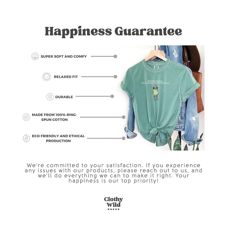 May include: A seafoam green t-shirt with a graphic of a frog wearing a hat and the text "Hold On Partner I'm Gonna Be A Little Froggy". The shirt is hanging on a wooden hanger. The image also includes text about the shirt's features.