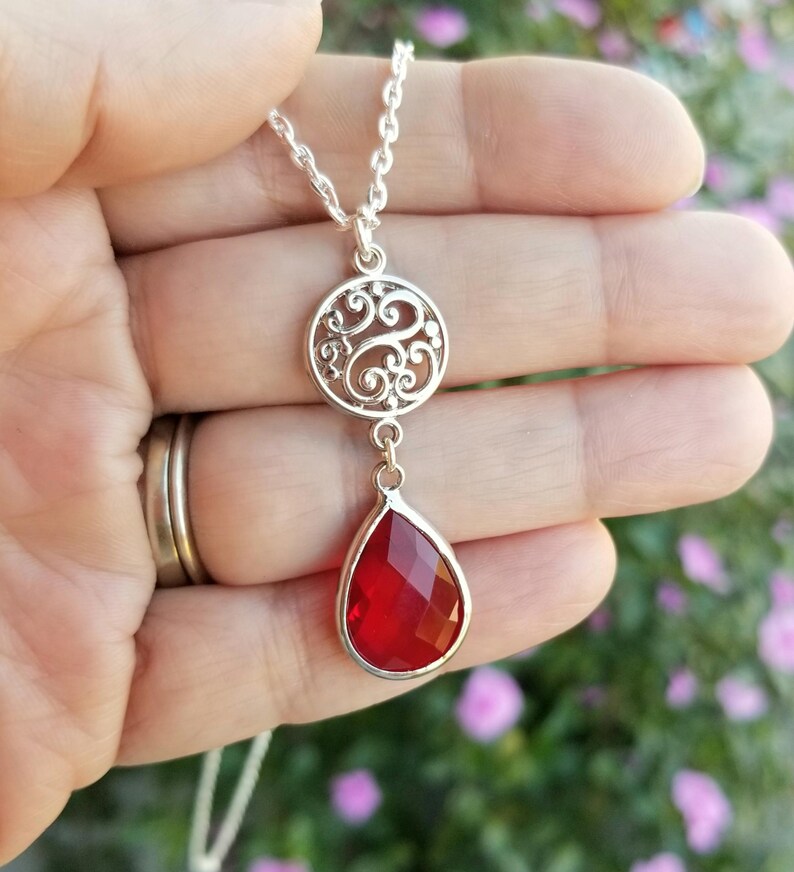 以下が含まれることがあります： 赤い涙型のペンダントとフィリグリーサークルのチャームが付いたシルバーネックレス