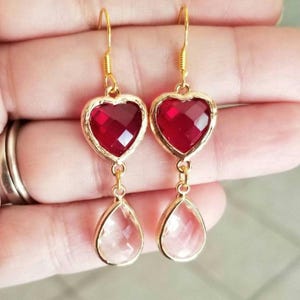 May include: Gold heart-shaped earrings with red crystal accents and clear teardrop-shaped crystals dangling below.