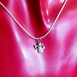 Puede incluir: Un collar de cadena de plata con un peque&ntilde;o colgante de &aacute;ngel. El &aacute;ngel tiene un halo y alas y est&aacute; adornado con peque&ntilde;os diamantes de imitaci&oacute;n transparentes.