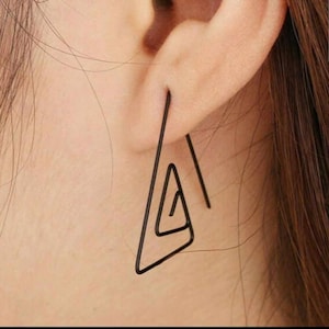 May include: A pair of black triangle shaped earrings with a geometric design.