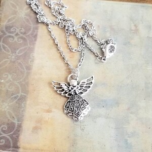 May include: A silver chain necklace with an angel pendant. The angel has detailed wings and a flowing gown.