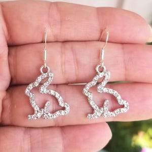 May include: A pair of silver dangle earrings featuring a rabbit silhouette design with clear rhinestones.