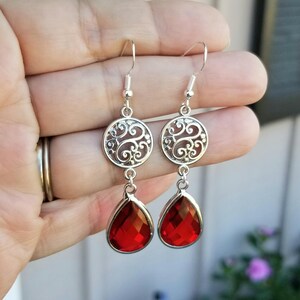 以下が含まれることがあります： 赤い雫型のクリスタルが付いた銀のフィリグリーイヤリング