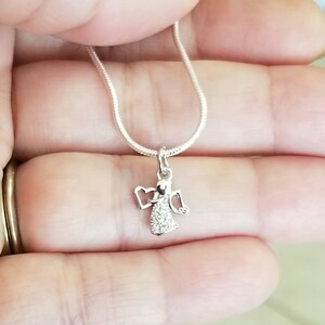 Puede incluir: Un collar de cadena de plata con un peque&ntilde;o colgante de &aacute;ngel de cristal transparente.