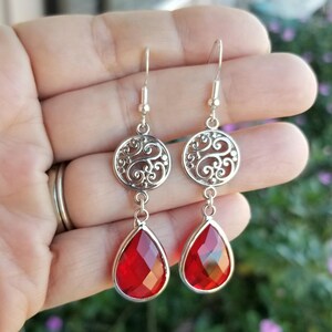 以下が含まれることがあります： 赤い涙型のクリスタルとフィリグリーのデザインが施されたシルバーのドロップイヤリング