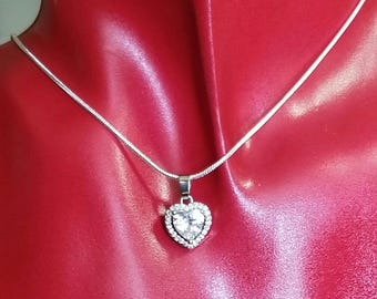 May include: A silver chain necklace with a heart-shaped pendant featuring a large clear crystal surrounded by smaller crystals.
