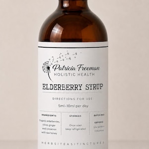 Peut inclure: Une bouteille en verre brun avec un bouchon à vis blanc contenant du sirop de sureau. L'étiquette présente un graphique de pissenlit, le texte Patricia Freeman Holistic Health, Elderberry Syrup, des instructions de 5ml-10ml par jour.