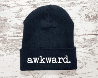 May include: Black beanie with the word "awkward" embroidered in white on the front.