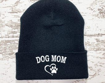 May include: Black knit beanie with a white paw print inside a heart and the text "DOG MOM" embroidered on the front.