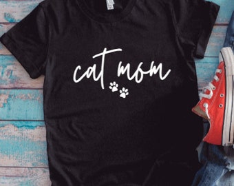 May include: Black t-shirt with the text "cat mom" in white lettering and two white paw prints.