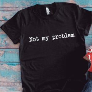 May include: Black t-shirt with white text that reads "Not my problem."