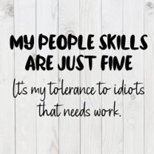 Może przedstawiać: Kwadratowy znak z napisem "MY PEOPLE SKILLS ARE JUST FINE. It's my tolerance to idiots that needs work." w czarnej czcionce. Tło to biały wzór słojów drewna.