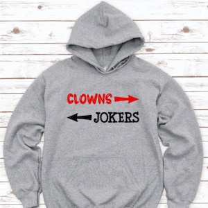 May include: A gray hooded sweatshirt with the text "Clowns" and an arrow pointing to the right, and the text "Jokers" with an arrow pointing to the left.