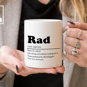 May include: White ceramic mug with a black and white design that says "Rad" and defines the word as "short for radical".