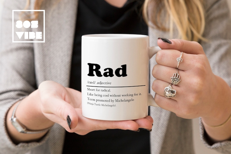 May include: White ceramic mug with a black and white design that says "Rad" and defines the word as "short for radical".