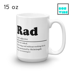 May include: White ceramic mug with a black and white design. The mug features the word "Rad" in bold black letters, followed by a definition: "rad/ adjective Short for radical. Like being cool without working for it. Term promoted by Michelangelo (Ninja Turtle Michelangelo)." The mug is 15 ounces.